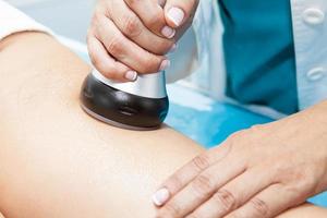 médico realizando a ultracavitação tratamento em uma jovem fêmea paciente perna foto