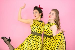 retro garotas. dois mulheres dentro amarelo vestidos em uma Rosa fundo. foto