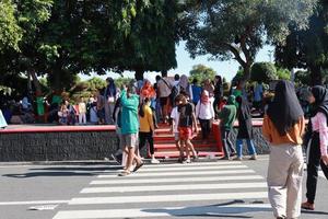 kudus, janeiro 2023. uma instantâneo do a multidões do carro livre dia visitantes cruzando a zebra cruzando para pegue para aluno aluno simpang 7 kudus. foto