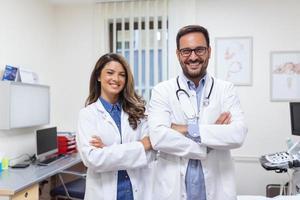 retrato do sorridente jovem médicos em pé junto. retrato do médico funcionários dentro moderno hospital sorridente para Câmera foto