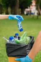 pessoas mão segurando lixo garrafa plástico e vidro colocando para dentro reciclar bolsa. plástico conceito. foto