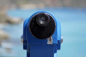 azul turista monocular em moedas e desfocado mar em segundo plano foto