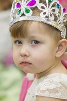 retrato do uma pequeno dois ano velho menina com uma coroa. foto