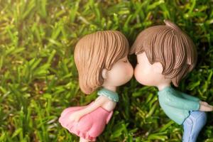 amor conceito ou dia dos namorados dia. casal se beijando boneca dentro romance em verde Relva fundo com cópia de espaço foto