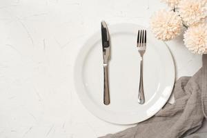 Comida conceito à moda mesa configuração talheres em branco mesa com prata garfo e faca foto