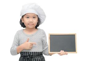 pequeno ásia menina chefe de cozinha dentro uniforme cozinhar segurando quadro-negro foto