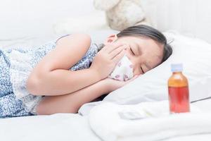 doente menina deitado dentro cama e dolorido garganta e tosse foto