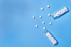 conceito do homeopático pílulas dentro garrafas em azul fundo. topo Visão foto
