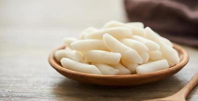 tteok ou coreano arroz bolos dentro uma de madeira prato em madeira mesa fundo foto