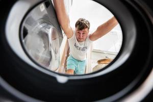 homem Visão a partir de lavando máquina dentro. masculino faz lavanderia diariamente rotina. foto