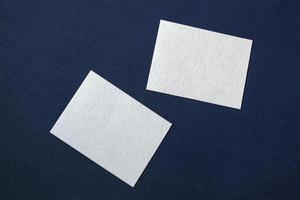 dois branco papel cartões em Sombrio azul texturizado fundo, aleatoriamente colocada o negócio modelo foto