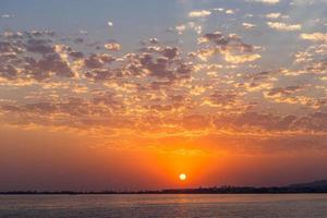 pôr do sol laranja colorido sobre um corpo de água foto