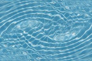 desfocar textura de superfície de água calma transparente de cor azul turva com salpicos e bolhas. fundo de natureza abstrata na moda. ondas de água na luz do sol com espaço de cópia. brilho da água azul foto