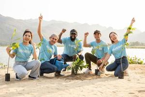grupo do voluntário sorridente amigos fazer punho bomba gesto sobre de praia. proteção do meio Ambiente e natureza, ecologia conceito. foto
