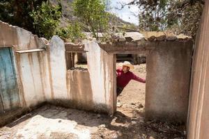 homem com uma vaqueiro chapéu olhando às a abandonado casa do dele avós dentro México foto