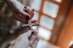 uma cruz de madeira nas mãos da mulher. foto
