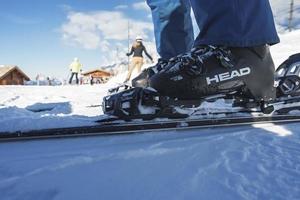 baixo seção do esquiador vestindo chuteiras e esqui em neve coberto declive foto