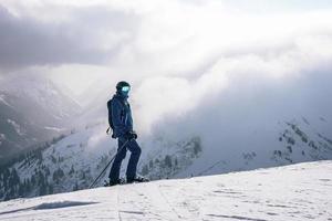 turista com esqui em pico do neve coberto montanha durante período de férias foto