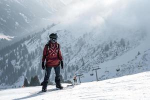 turista em pé em pico do neve coberto montanha durante período de férias foto