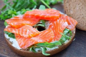 sanduíche de bagel com salmão na mesa de madeira foto