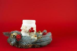 Natal cartão. Natal castiçal decorado com galhos do uma Natal árvore com vermelho bagas e Natal bolas do ouro cor em uma vermelho fundo foto