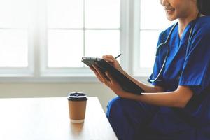 ásia enfermeira com confiança trabalhando em computador portátil dentro clínica. feliz médico ou enfermeira dentro hospital foto