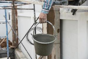 construtor contratante homem trabalho segurando misturar fresco concreto dentro indústria trabalhos projeto, preparar para derramar molhado líquido material para dentro a Formato dentro construção local Como profissional emprego foto