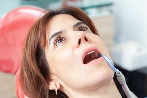 lindo mulher tendo dental tratamento às Dentistas escritório. foto