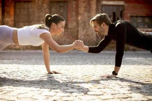 casal jovem bonito fazendo exercícios de flexão de braço em ambiente urbano