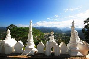 lindo branco pagode e leão escultura com azul céu localizado ao longo a penhasco em a montanha dentro phra este doi kong mu têmpora às Meahongson província, Tailândia foto