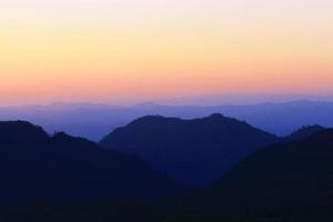 pôr do sol dentro céu e nuvem, lindo colorida crepúsculo Tempo com silhueta do montanha. foto