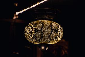 original oriental luminária brilhando com caloroso luz durante a chegando Sombrio foto