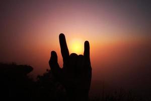 lindo silhueta do dedos e mão com vale do montanha dentro nebuloso e névoa do nascer do sol brilhando em a céu foto