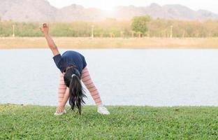 fofa menina exercício em verde grama, saudável foto