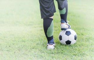 futebol bola com criança pés jogador em verde Relva foto