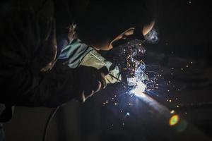 soldador às trabalhar. homem dentro uma protetora mascarar. a soldador faz costuras em a metal. faíscas e fumaça quando Soldagem. foto