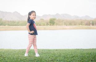 fofa ásia menina exercício em verde Relva foto