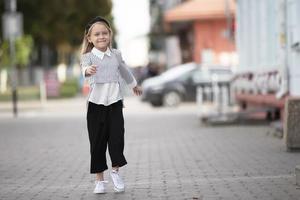 alegre pequeno menina em a rua do a cidade. uma criança dentro a urbano contexto. foto