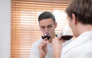 lgbt jovem casal comemoro a dia do amor entre cada de outros com bem vinho dentro a cozinha do a casa foto