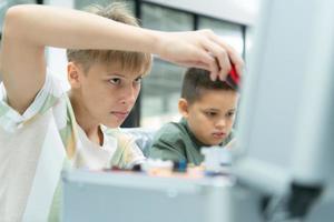 jovens utilizando a mão robô tecnologia estão tendo Diversão Aprendendo a eletrônico o circuito borda e mão robô controlador do robô tecnologia, que é 1 do a haste cursos. foto