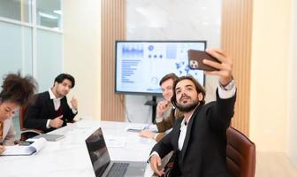 uma diverso grupo do jovem o negócio pessoas levando selfies dentro a conferência quarto do a internacional o negócio companhia enquanto esperando para a encontro para começar foto