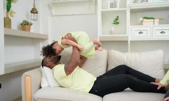 pai tendo Diversão com dele filha de jogando acima e elevação dela acima enquanto a mãe é ao lado. foto