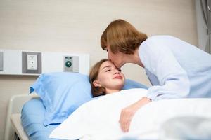uma mãe cobertores dela criança quem é hospitalizado. mostrar seu amor e preocupação com uma beijo antes hora de dormir. foto