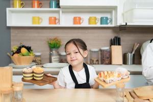 retrato do uma pequeno menina dentro a cozinha do uma casa tendo Diversão jogando cozimento pão foto