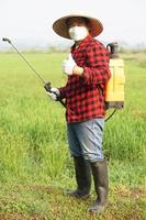 bonito ásia agricultor é pulverização orgânico fertilizante às arroz campo. conceito usando amigáveis produtos com meio Ambiente , agricultura com não produtos químicos usando. segurança com do utilizador e ambiente. foto