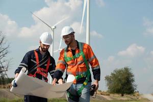 agrimensor e engenheiro examinar a eficiência do gigantesco vento turbinas este transformar vento energia para dentro elétrico energia este é então usava dentro diariamente vida. foto