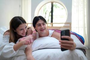 jovem casal dentro a quarto dentro a manhã, dizer Oi para Parceiros conectados usando Smartphone. foto