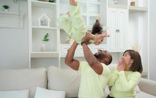 pai tendo Diversão com dele filha de jogando acima e elevação dela acima enquanto a mãe é ao lado. foto