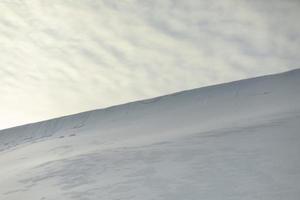 encosta nevada contra o céu. avalanche de neve no cume da montanha. clima frio. foto