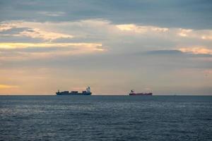 logística importar exportação recipiente carga navio dentro Porto Maritimo em pôr do sol céu, frete transporte de recipiente navio barco foto